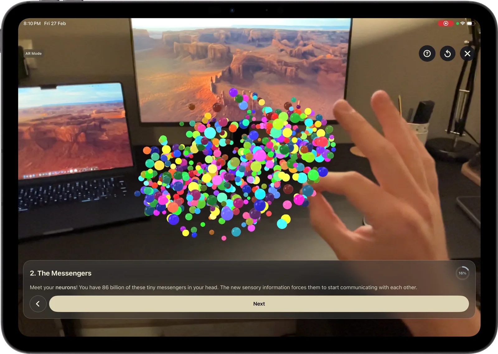 Augmented reality mode on an iPad Pro: neurons placed on a desk, a hand reaching toward them